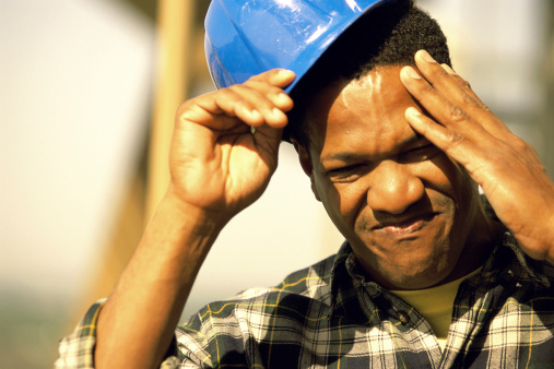 Close-up of a construction worker touching his head and removing his hardhat